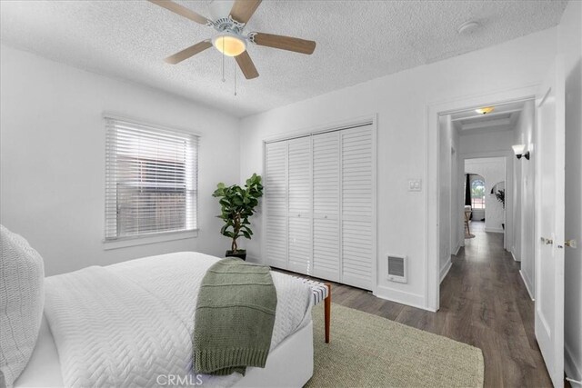 bedroom featuring ceiling fan, dark wood-type flooring, a textured ceiling, and a closet