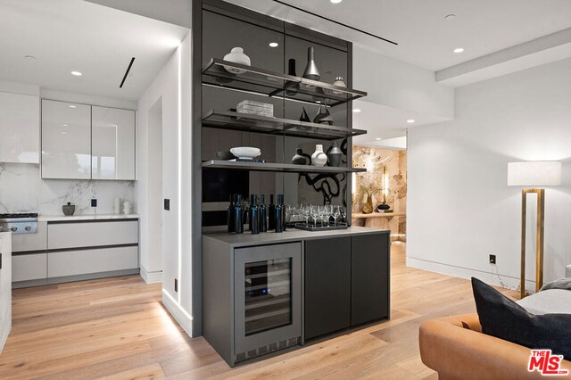 bar featuring white cabinets, backsplash, and light hardwood / wood-style floors