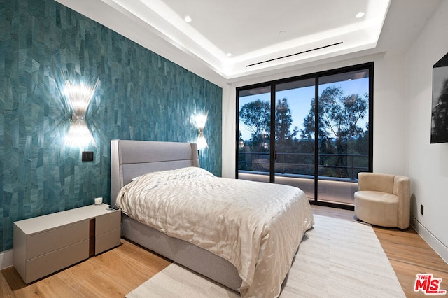 bedroom featuring light hardwood / wood-style flooring and a raised ceiling