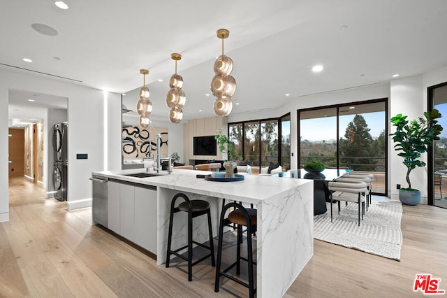 kitchen featuring pendant lighting, white cabinets, dishwasher, a large island with sink, and sink