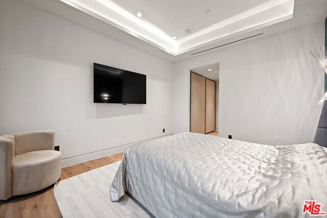 bedroom featuring a tray ceiling and light hardwood / wood-style flooring