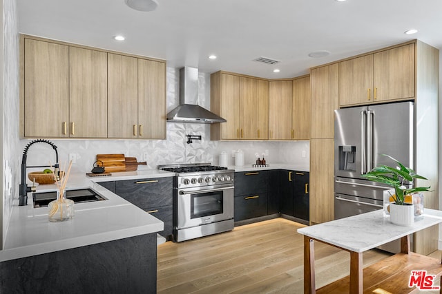 kitchen featuring wall chimney exhaust hood, tasteful backsplash, light hardwood / wood-style floors, sink, and high end appliances