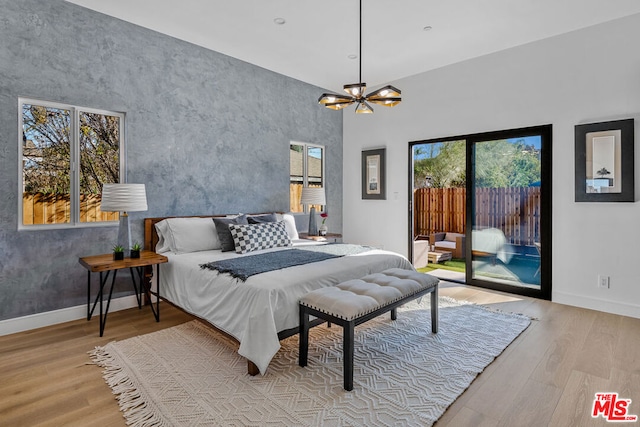 bedroom featuring a chandelier, light hardwood / wood-style flooring, and access to outside