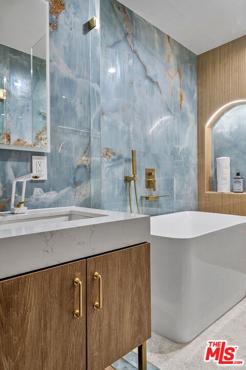 bathroom with tile walls, vanity, and a bath