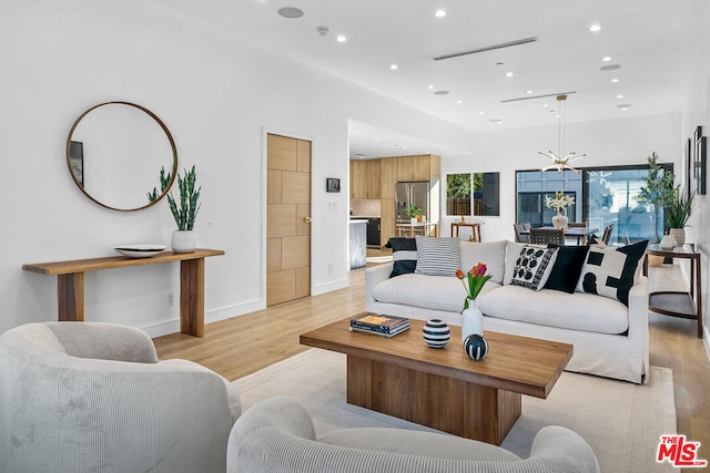 living room with an inviting chandelier, light hardwood / wood-style floors, and plenty of natural light