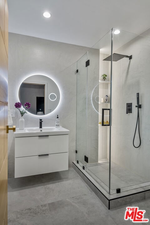 bathroom featuring a shower with shower door and vanity