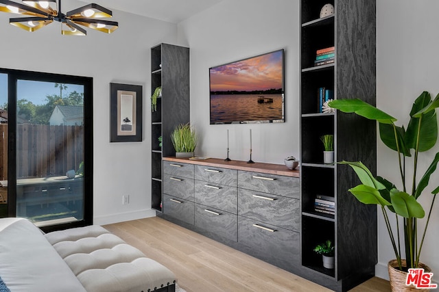 living room featuring light wood-type flooring, a notable chandelier, and built in shelves