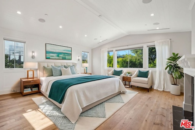 bedroom with light wood-type flooring, vaulted ceiling, and multiple windows