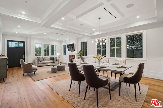 dining room featuring crown molding, beam ceiling, light hardwood / wood-style floors, and coffered ceiling