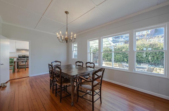 dining space with crown molding, a chandelier, and light wood-type flooring