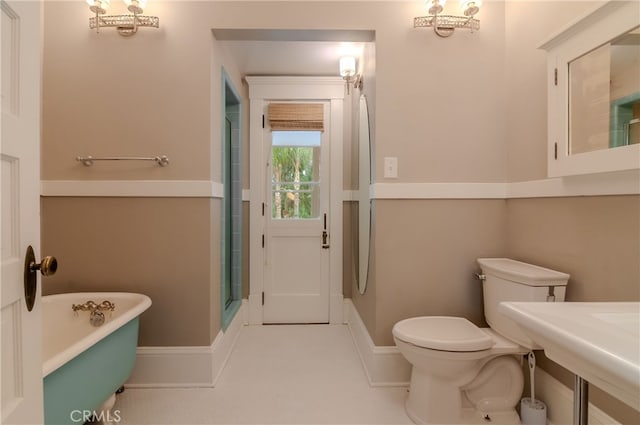 bathroom with a tub to relax in and toilet