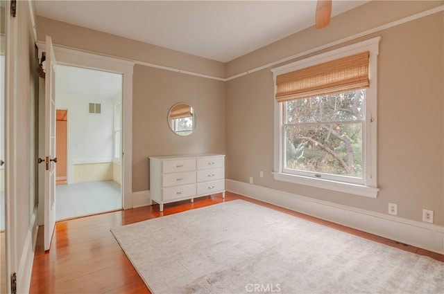 unfurnished bedroom featuring ceiling fan, connected bathroom, and light hardwood / wood-style flooring