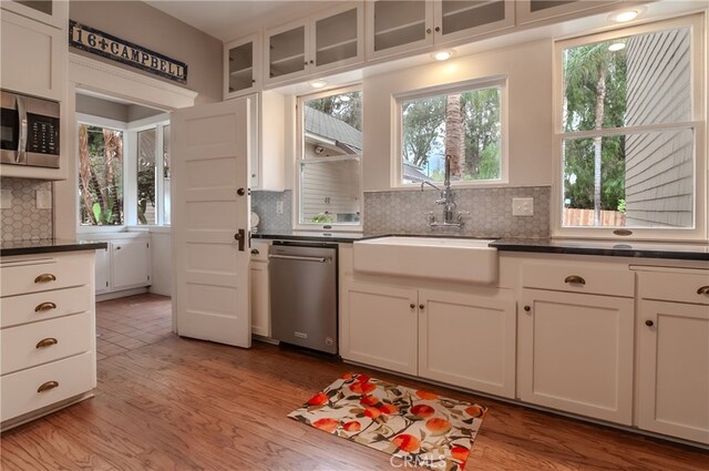 kitchen with decorative backsplash, sink, white cabinetry, light wood-type flooring, and stainless steel appliances