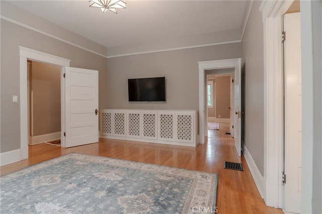 unfurnished living room with light wood-type flooring and ornamental molding