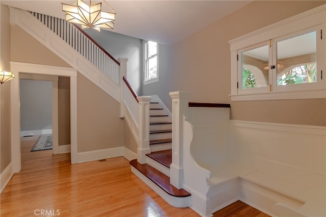 staircase featuring an inviting chandelier and hardwood / wood-style flooring