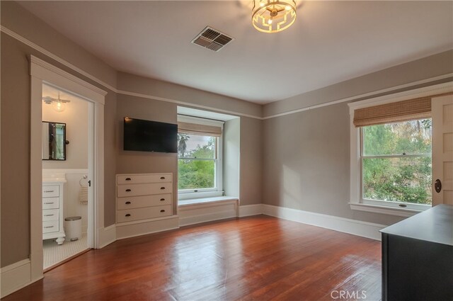 bedroom with ensuite bathroom, hardwood / wood-style flooring, and multiple windows