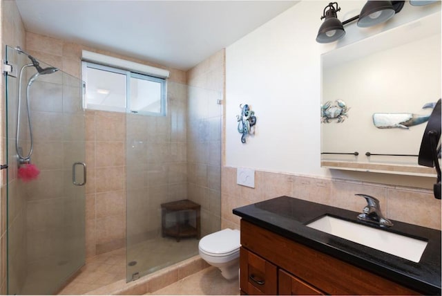 bathroom featuring toilet, a shower with door, tile patterned flooring, tile walls, and vanity