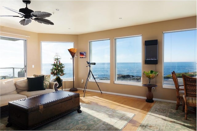 living room with a water view, ceiling fan, and wood-type flooring