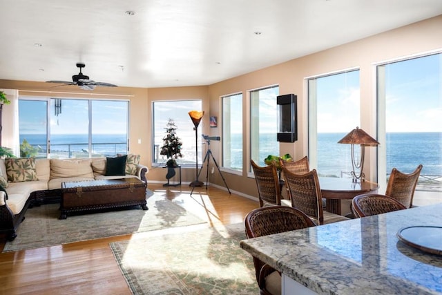 living room featuring ceiling fan, light hardwood / wood-style floors, and a water view