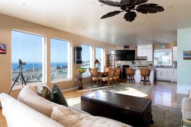 living room with a water view, ceiling fan, and light wood-type flooring