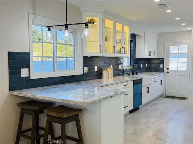 kitchen with dishwashing machine, a kitchen breakfast bar, light stone counters, and white cabinetry