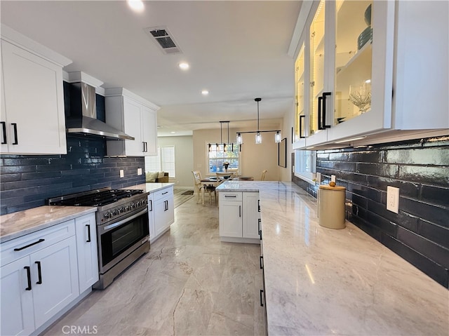 kitchen with light stone countertops, pendant lighting, white cabinets, and high end stove