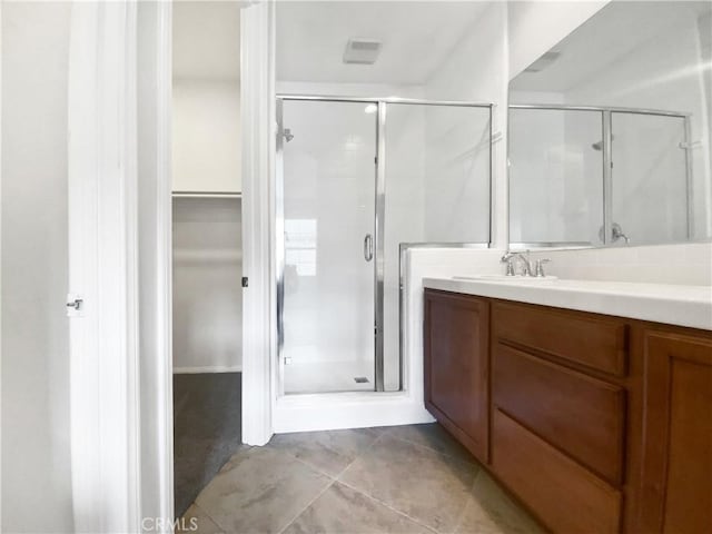 bathroom with tile patterned flooring, a shower stall, vanity, and a walk in closet