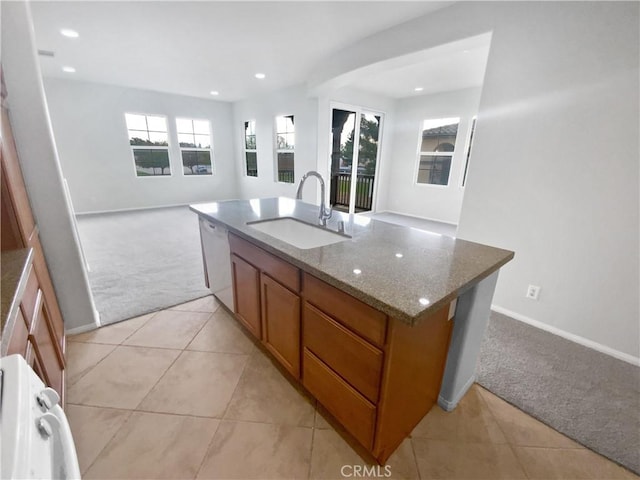 kitchen featuring a center island with sink, light colored carpet, dishwasher, light stone counters, and sink