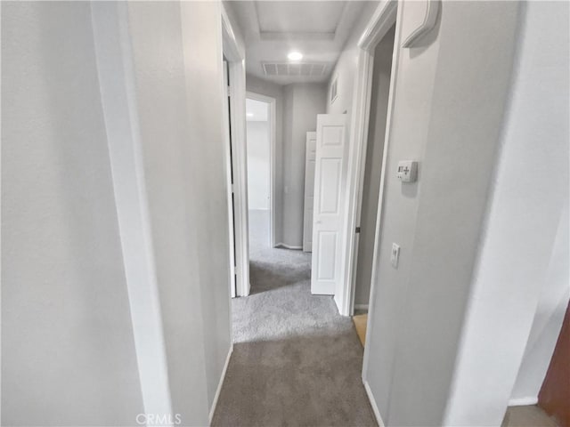 hallway with dark colored carpet, visible vents, and baseboards