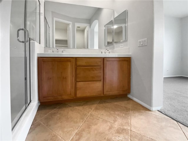 bathroom featuring a stall shower, baseboards, a sink, and tile patterned floors