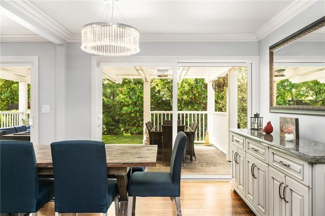 dining room featuring light wood-type flooring, an inviting chandelier, and ornamental molding