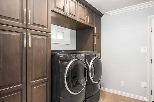 laundry room with light tile patterned floors, crown molding, washing machine and clothes dryer, and cabinets