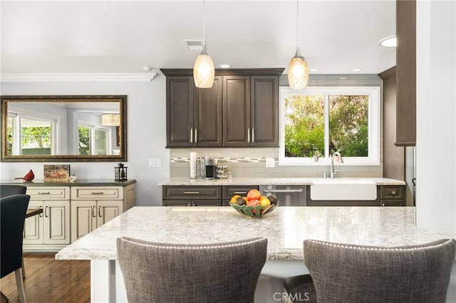 kitchen featuring a breakfast bar area, sink, dishwasher, and light stone countertops