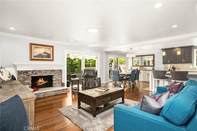 living room featuring dark hardwood / wood-style flooring, ornamental molding, and a stone fireplace