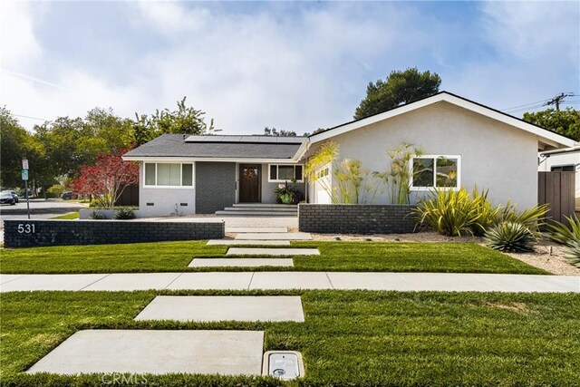 view of front of home with a front lawn and solar panels