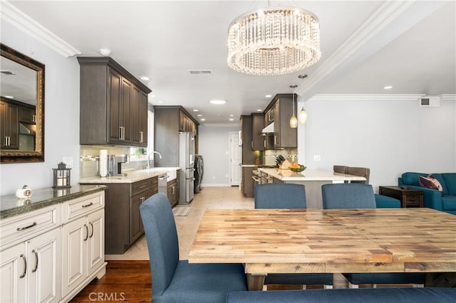 dining room with light wood-type flooring, ornamental molding, and a notable chandelier