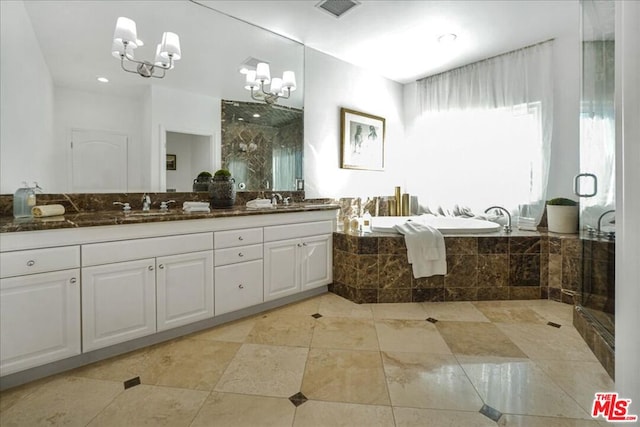 bathroom with tiled bath, vanity, and an inviting chandelier