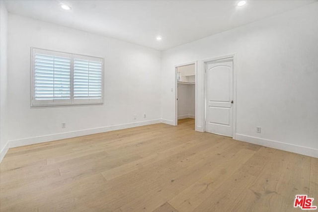 unfurnished bedroom featuring a closet, a spacious closet, and light hardwood / wood-style floors