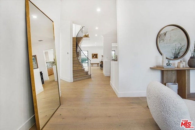 hallway with light wood-type flooring and crown molding