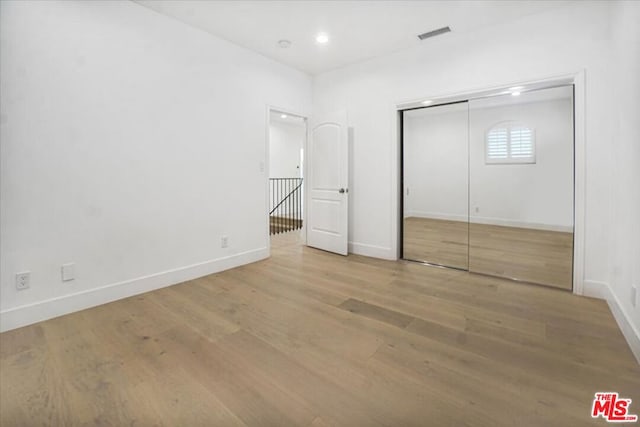 unfurnished bedroom with light wood-type flooring and a closet