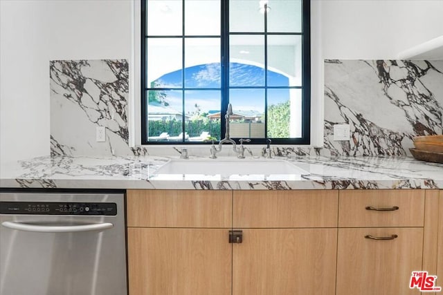 kitchen featuring stainless steel dishwasher, light brown cabinets, a wealth of natural light, and light stone counters