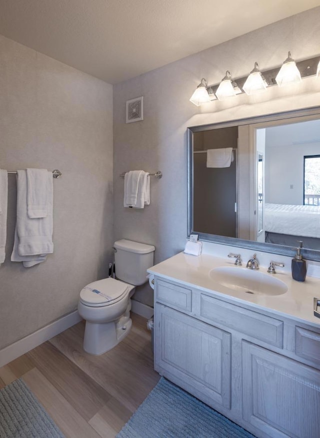 bathroom with wood-type flooring, toilet, and vanity