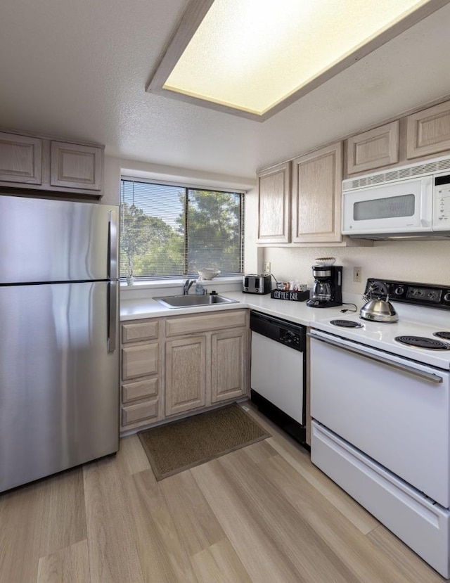 kitchen featuring sink, white appliances, light hardwood / wood-style flooring, light brown cabinets, and a textured ceiling