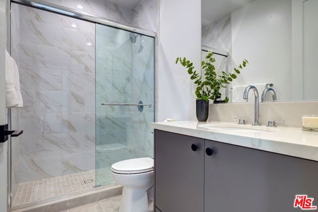 bathroom featuring toilet, tile patterned flooring, a shower with shower door, and vanity