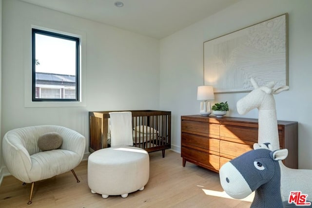 bedroom with light wood-type flooring and a crib