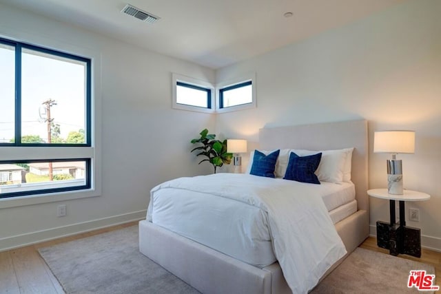 bedroom with multiple windows and light hardwood / wood-style floors