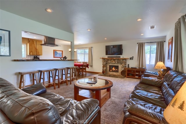 carpeted living room featuring a stone fireplace