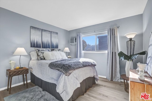 bedroom featuring a wall mounted AC and light hardwood / wood-style flooring