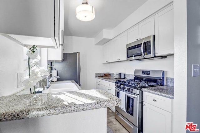 kitchen featuring white cabinets, kitchen peninsula, sink, and stainless steel appliances