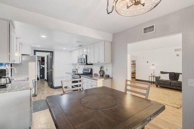 dining area featuring sink, light hardwood / wood-style flooring, and a notable chandelier